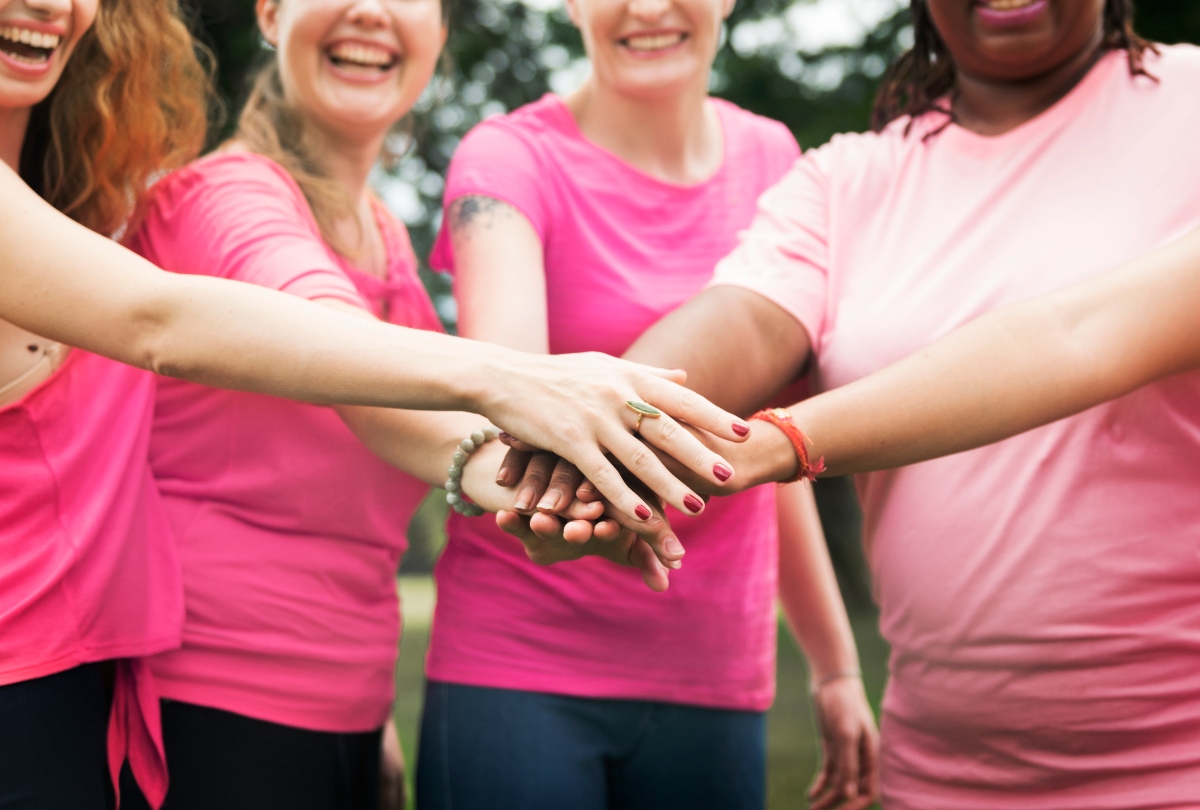 women holding hands, women smiling, women dressed in pink, Cancer Month, QuéOnnda