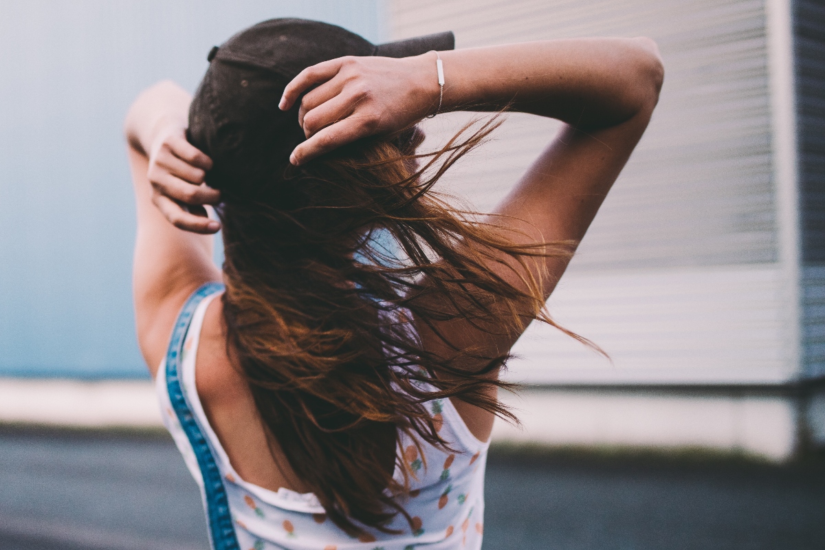 mujer con viento, cabello de mujer viento, mujer con gorra, mujer de espaldas, QuéOnnda